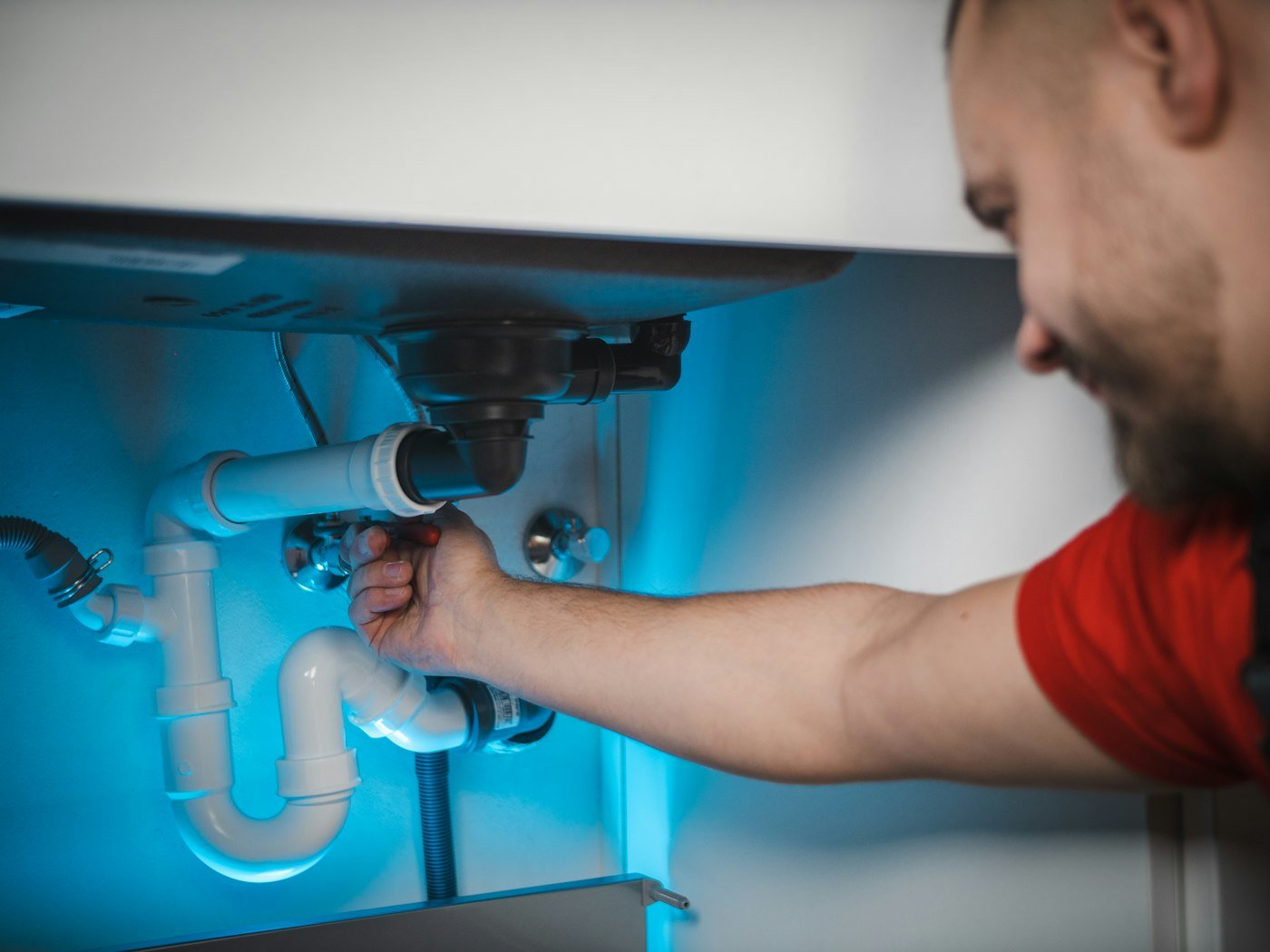 Instalator profesionist reparând o instalație sanitară într-o locuință modernă
